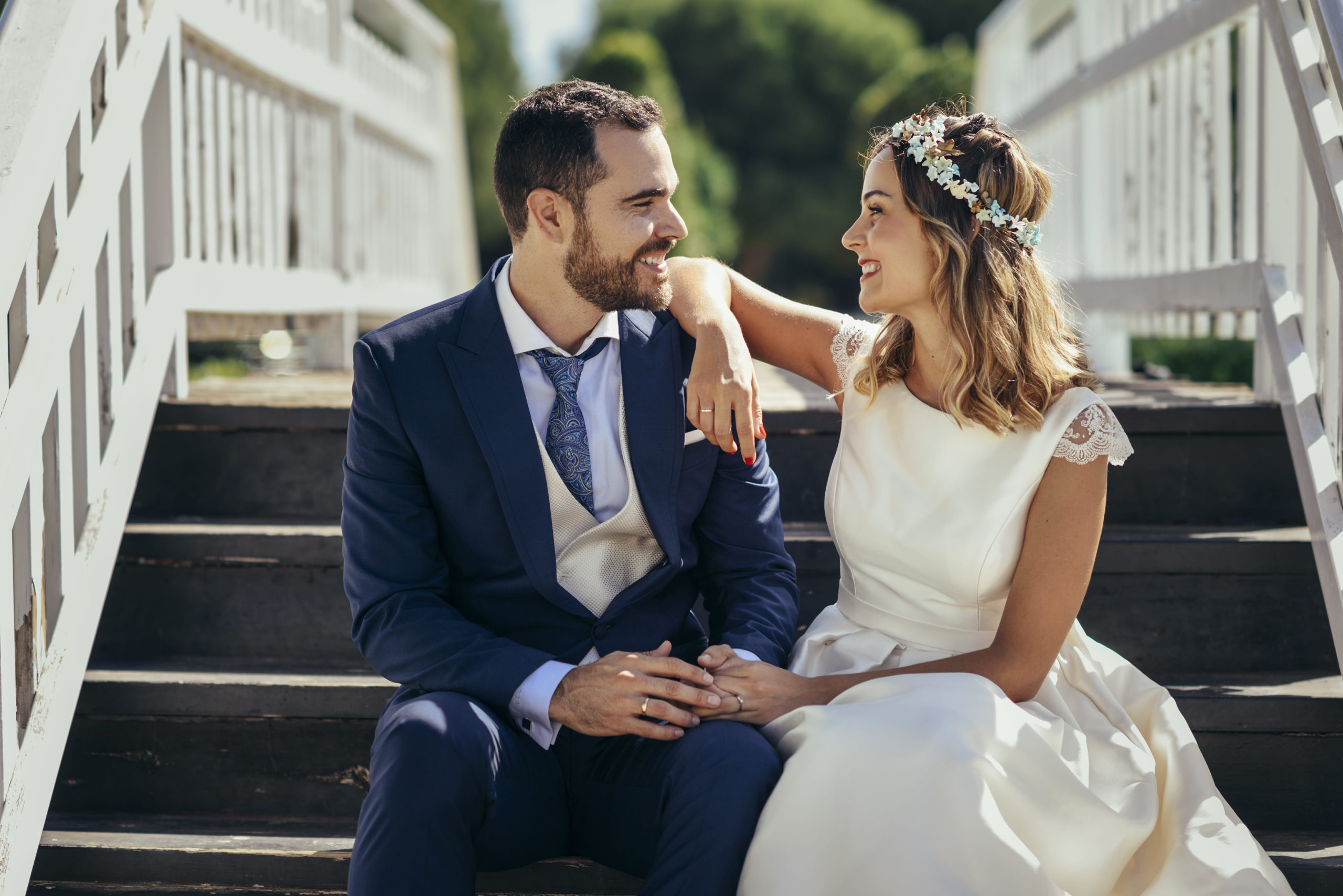 Happy bridal couple sitting on stairs holding hands