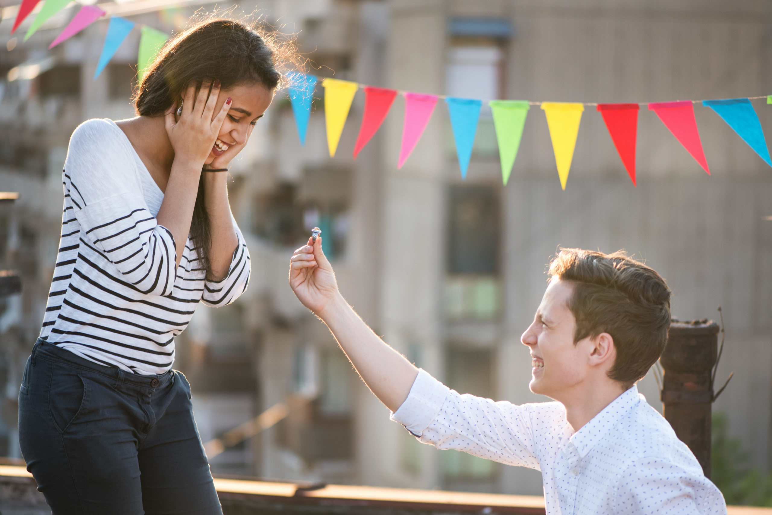 Kneeling young man proposing to his girlfriend. Should they get ring insurance?