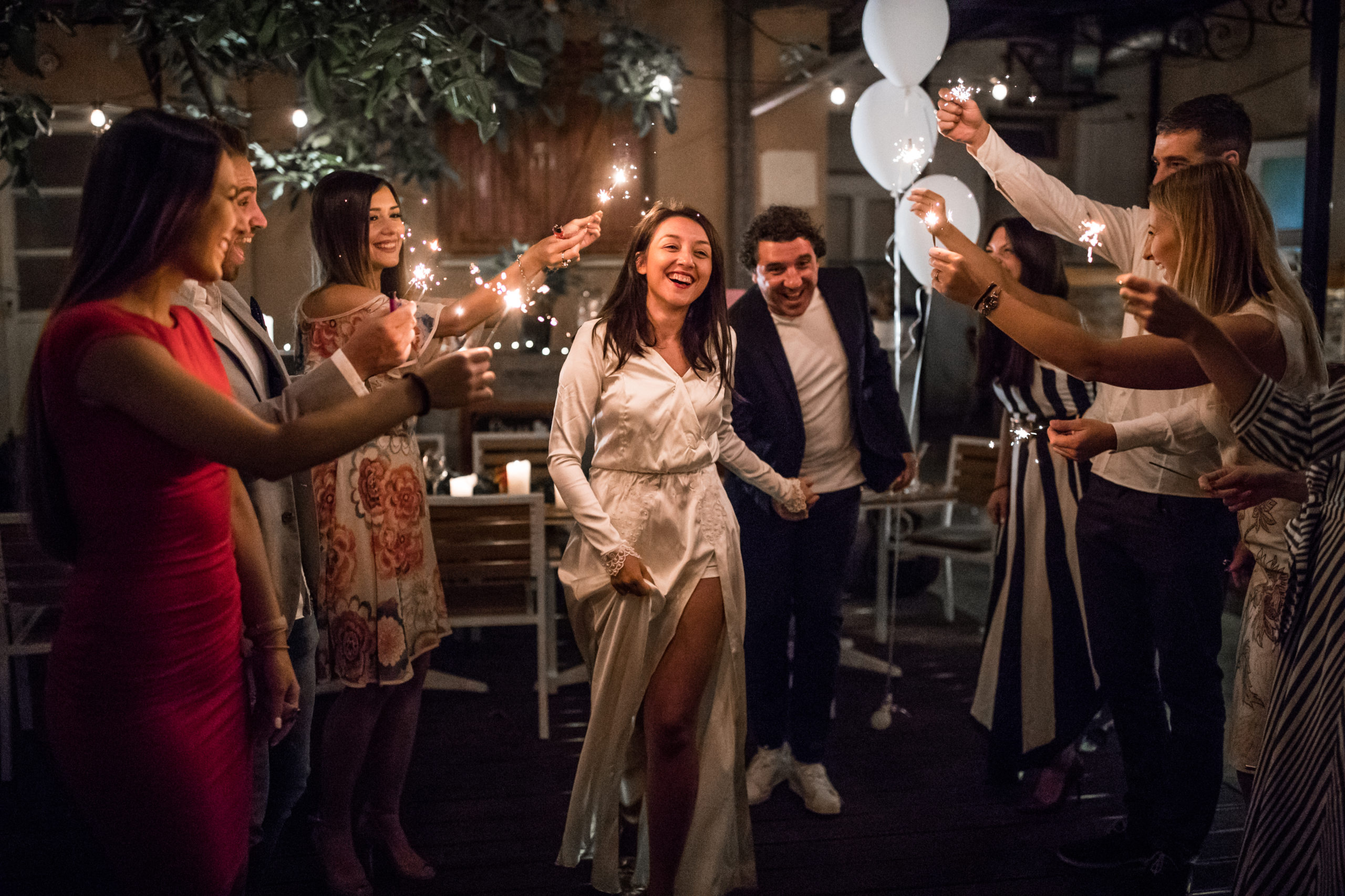 Just married couple showing up before their friends and running through the tunnel of sparklers