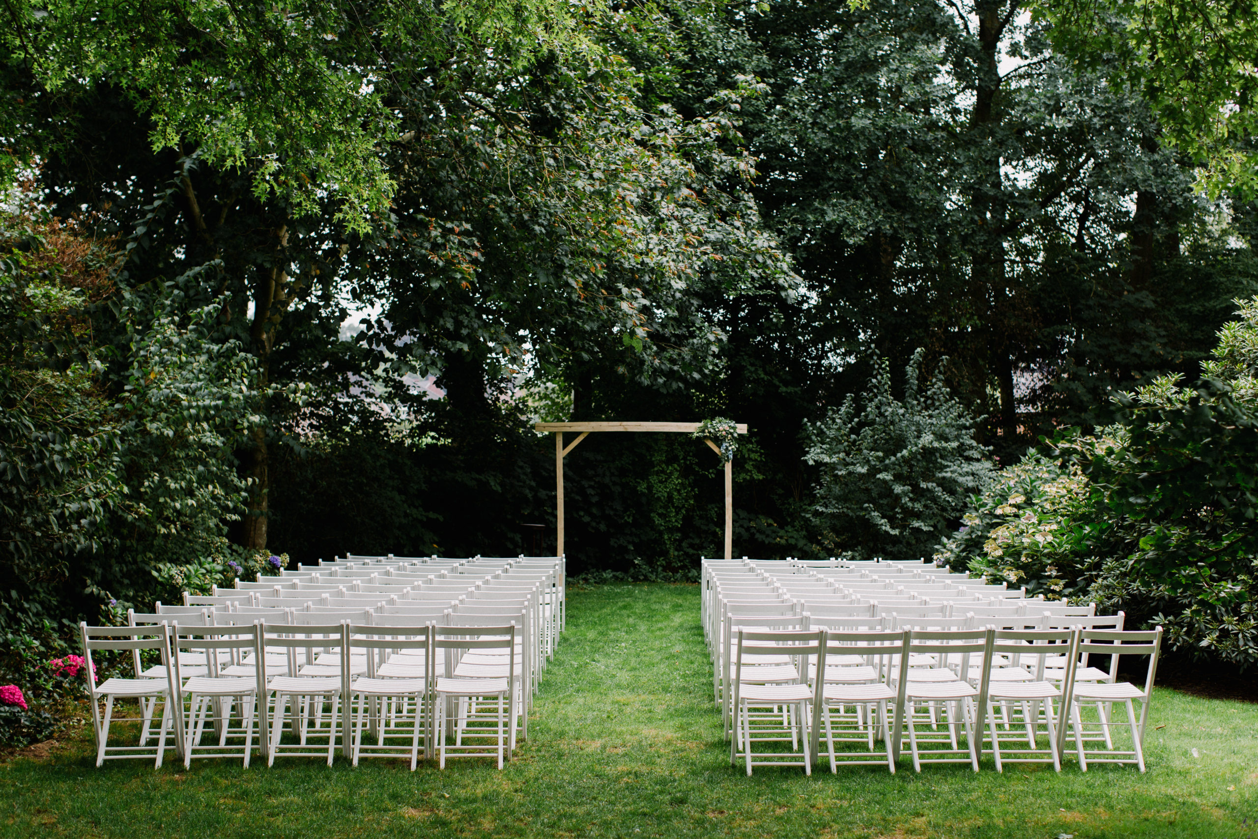 Garden scenery, lots of white chairs lined up before the wedding ceremony. Outdoor wedding ceremony.