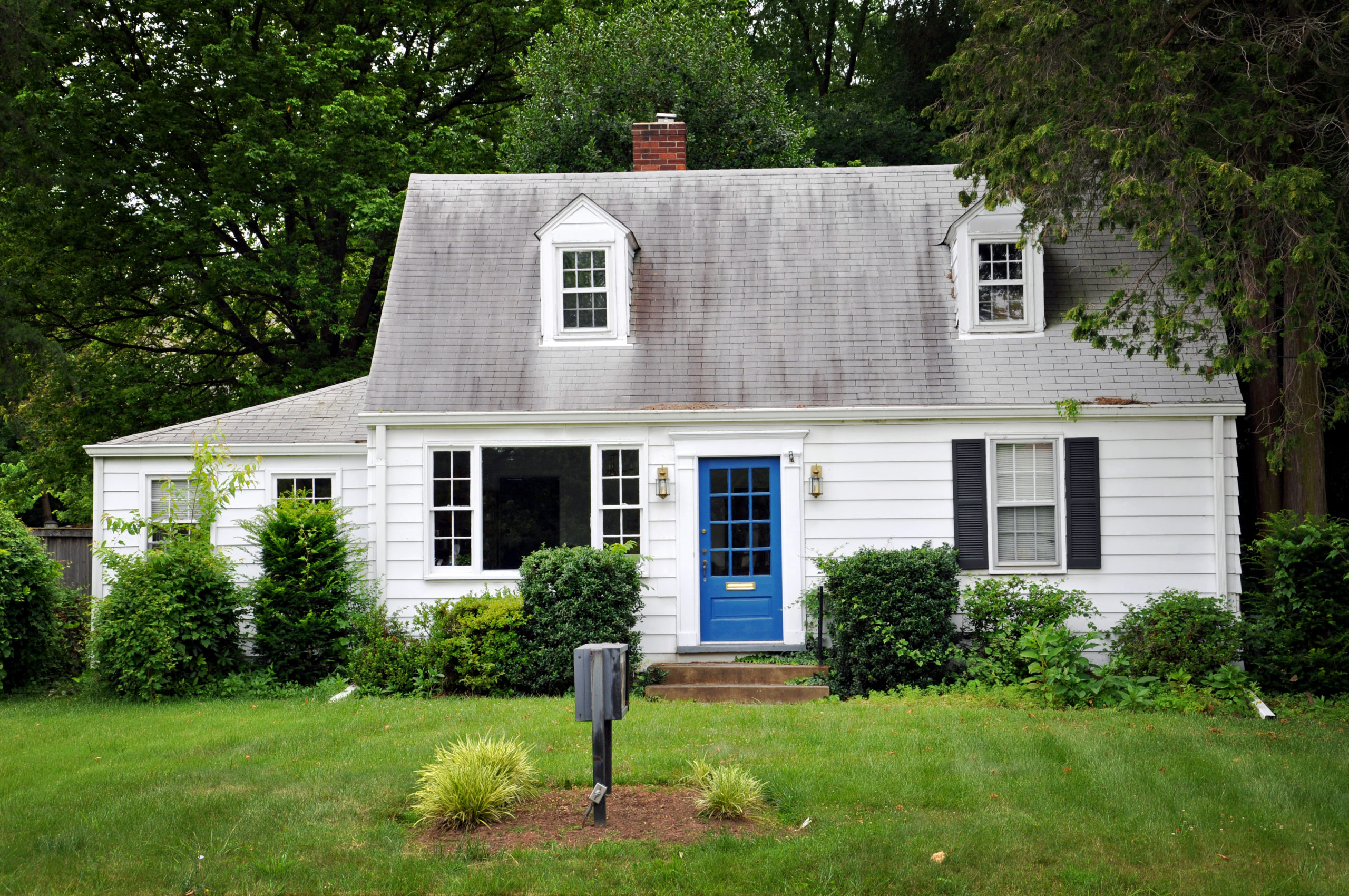 Fixer upper house that is white with a blue door