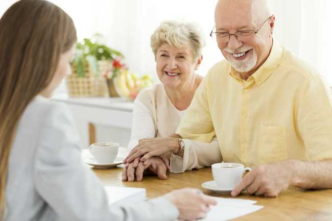 senior man and woman smiling at woman helping them with life insurance