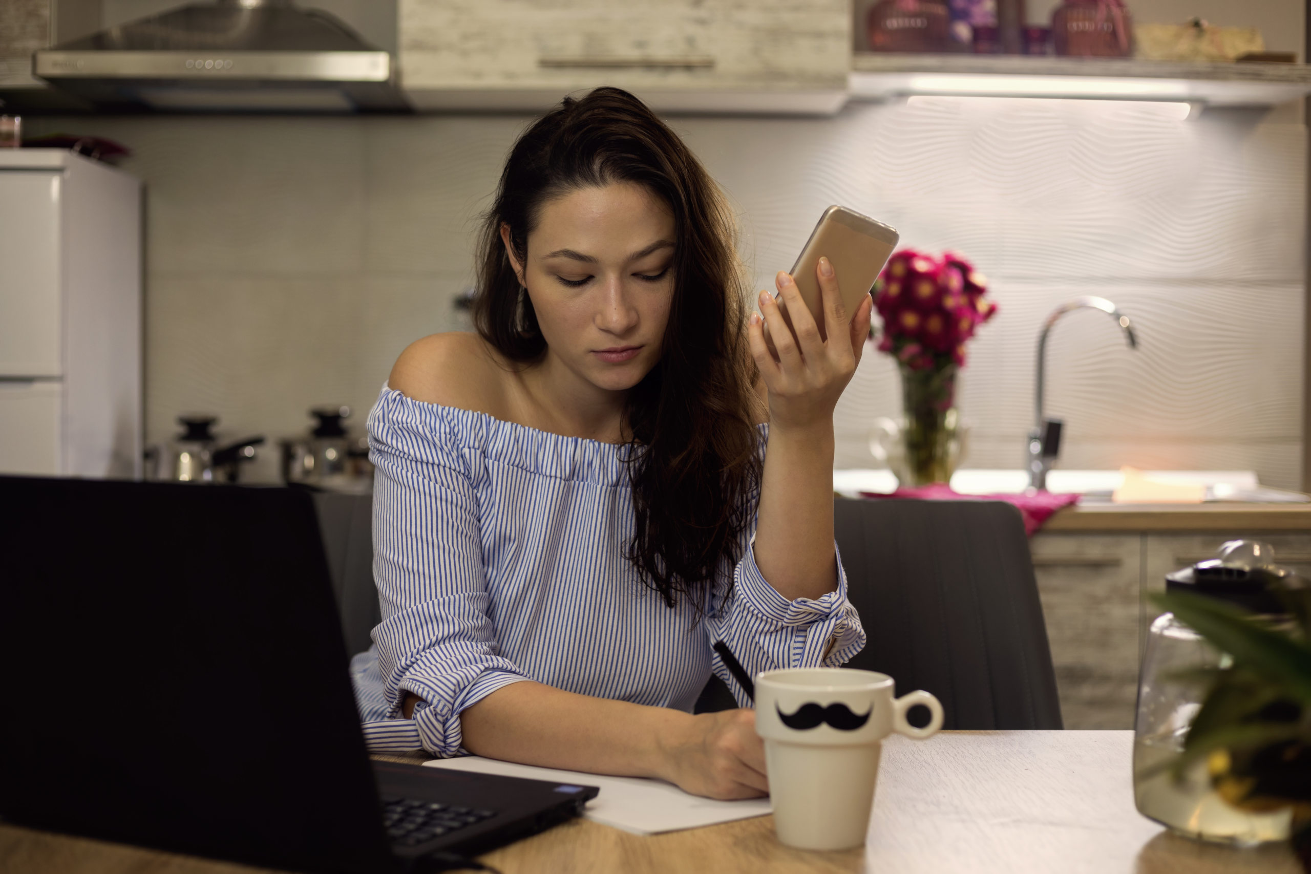 young woman sits at table trying to figure out how she will pay this month's rent