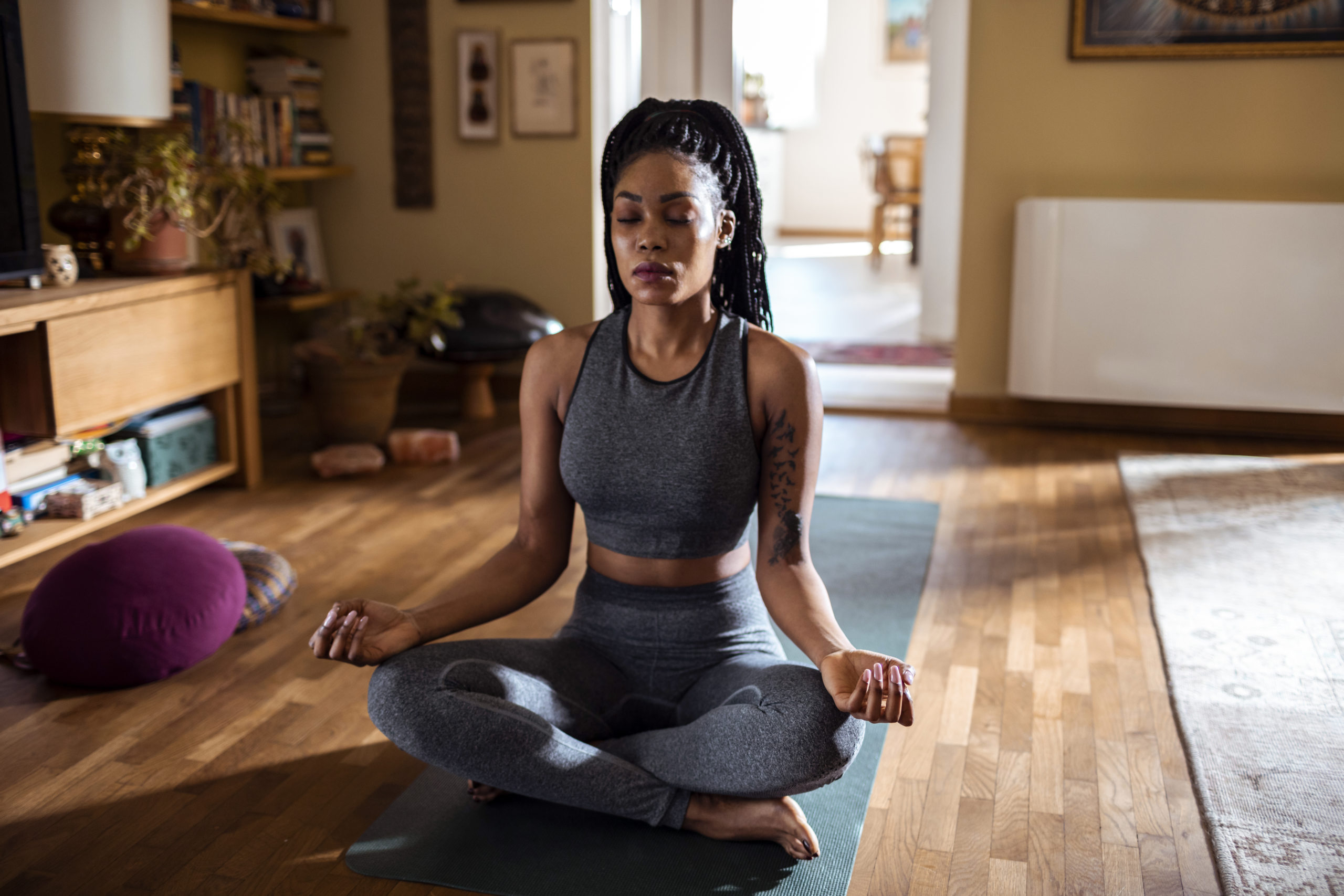 Close-up of a young woman meditating on a yoga mat and practicing self-care at home