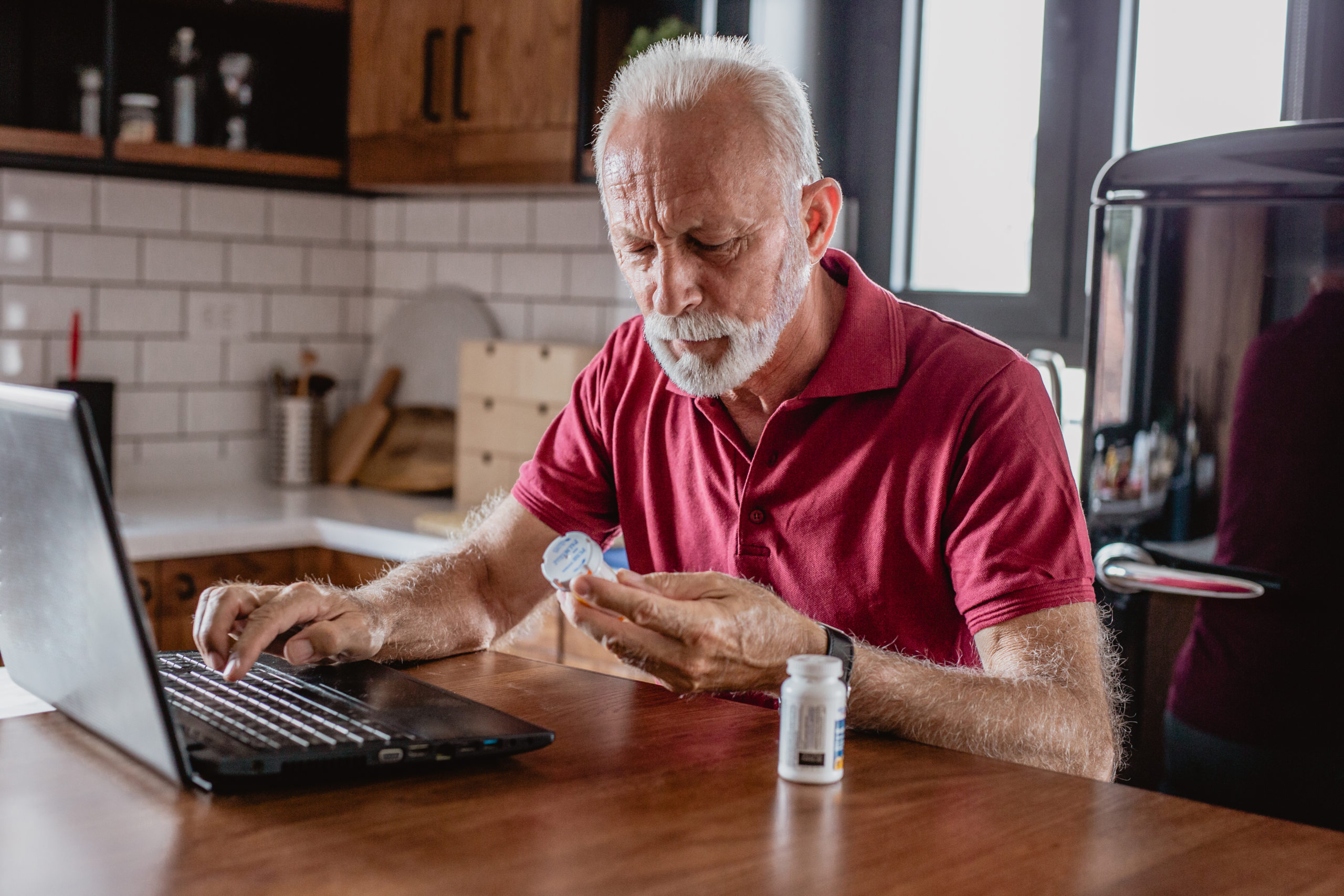 Older man researches online to identify a potential coronavirus scam regarding a fake treatment or vaccine for COVID-19