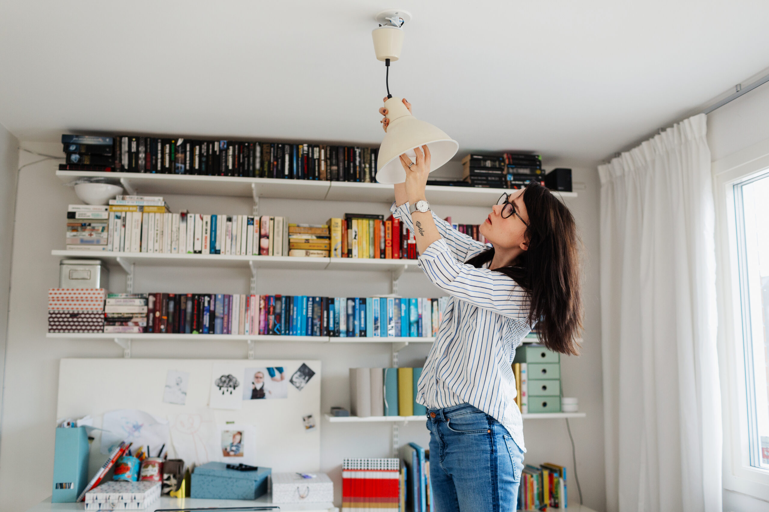 woman changing lightbulb and performing home maintenance, one of the hidden costs of buying a home