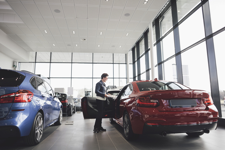 woman examining the make and model of a car in a dealership
